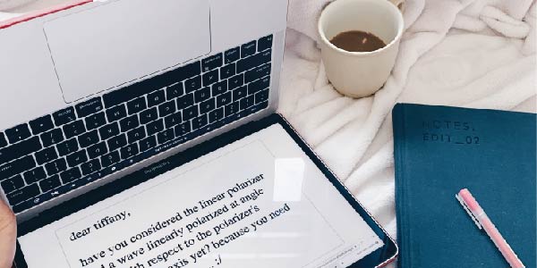 aerial view of upside down laptop with text on screen, coffee cup, notebook, and pen